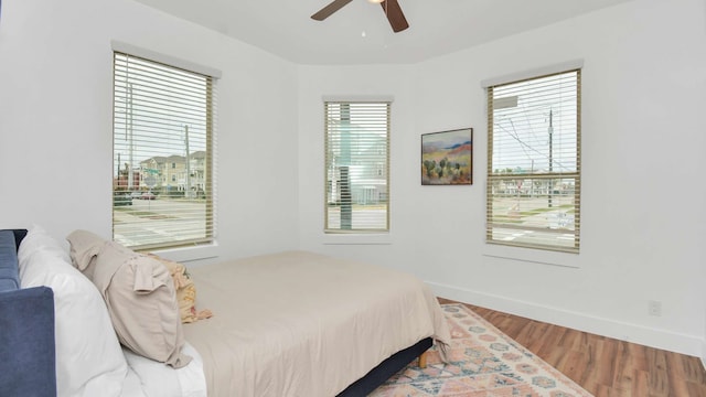 bedroom with ceiling fan, multiple windows, and wood-type flooring