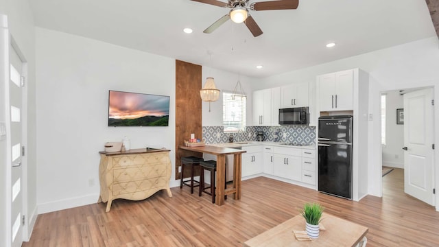 kitchen featuring light hardwood / wood-style floors, white cabinetry, and black appliances