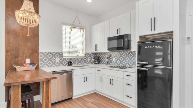 kitchen featuring white cabinetry, black appliances, sink, light wood-type flooring, and tasteful backsplash