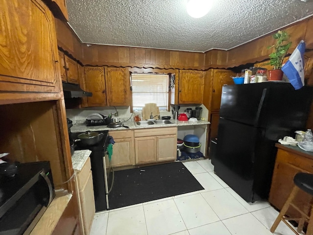 kitchen featuring a textured ceiling, sink, light tile floors, and black appliances