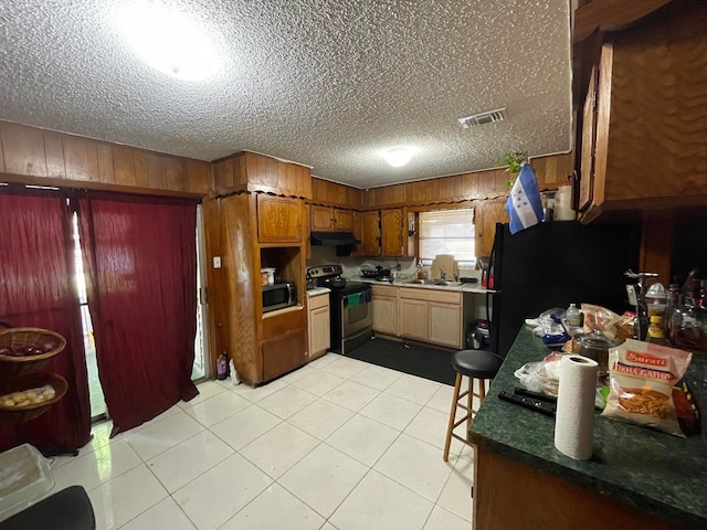 kitchen with light tile flooring, stainless steel appliances, a textured ceiling, and sink