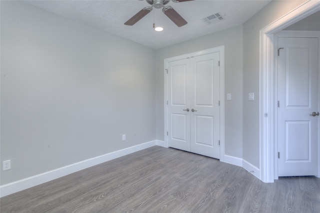 unfurnished bedroom featuring dark hardwood / wood-style flooring, a closet, and ceiling fan