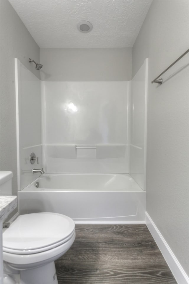 bathroom with shower / tub combination, toilet, and a textured ceiling