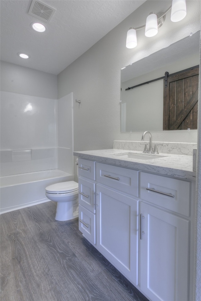 full bathroom featuring toilet, wood-type flooring, shower / tub combination, a textured ceiling, and vanity