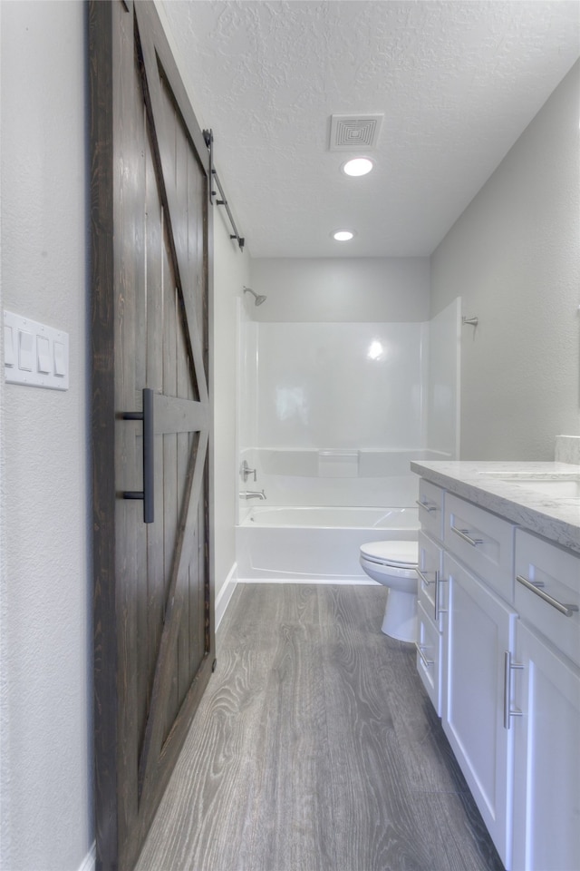 full bathroom featuring  shower combination, a textured ceiling, toilet, hardwood / wood-style flooring, and vanity