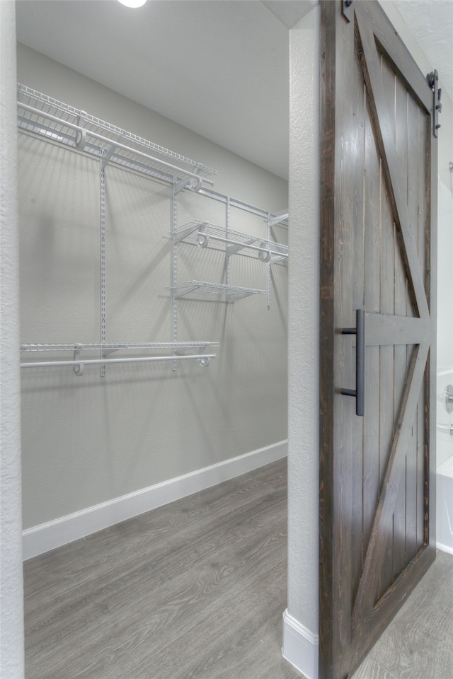 walk in closet featuring a barn door and wood-type flooring