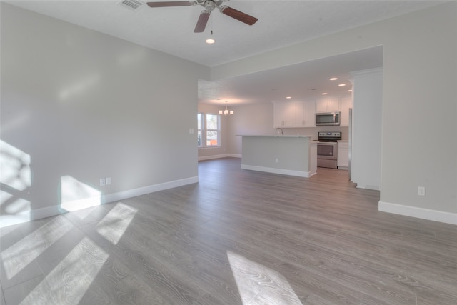 unfurnished living room featuring light hardwood / wood-style floors, ceiling fan with notable chandelier, and sink