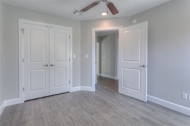 unfurnished bedroom with ceiling fan, a closet, and light wood-type flooring