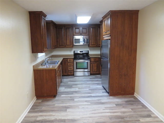 kitchen with light wood-type flooring, sink, and stainless steel appliances