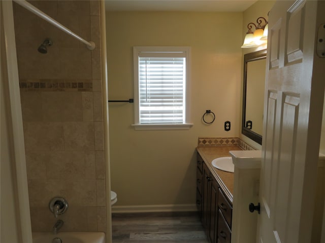 full bathroom featuring tiled shower / bath combo, vanity, hardwood / wood-style floors, and toilet