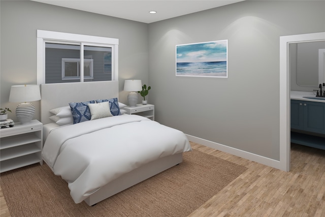 bedroom featuring ensuite bath, light wood-type flooring, and sink