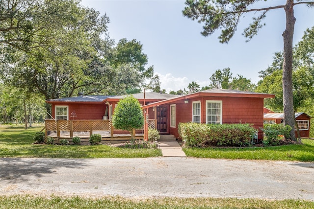 ranch-style house featuring a front lawn and a deck