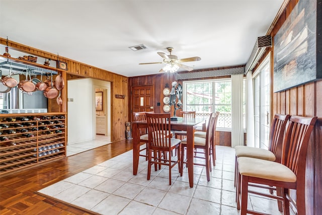 dining space featuring ceiling fan, wooden walls, and parquet flooring