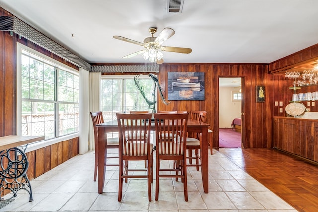 tiled dining room with ceiling fan and wooden walls