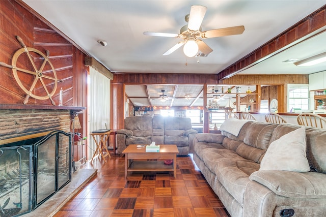 living room with ceiling fan, a wealth of natural light, and wooden walls