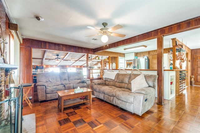 living room featuring ceiling fan, parquet floors, and wood walls