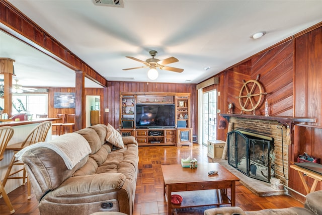 living room with ceiling fan, wooden walls, and parquet flooring