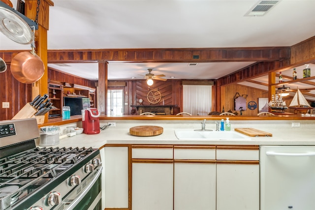 kitchen featuring ceiling fan, wooden walls, double oven range, dishwasher, and sink