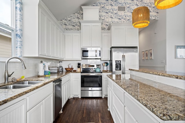 kitchen with sink, stainless steel appliances, dark wood-type flooring, light stone countertops, and white cabinetry