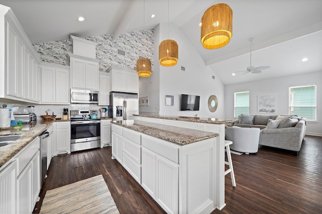 kitchen featuring dark wood-type flooring, ceiling fan, stainless steel appliances, decorative light fixtures, and high vaulted ceiling