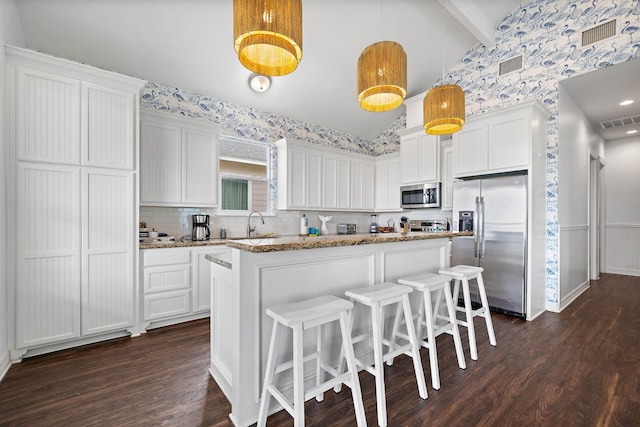 kitchen with dark hardwood / wood-style floors, stainless steel appliances, white cabinets, tasteful backsplash, and pendant lighting