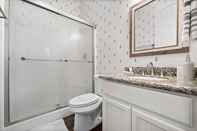 bathroom featuring toilet, vanity, an enclosed shower, and wood-type flooring