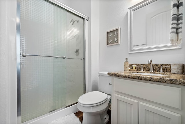 bathroom featuring a shower with door, toilet, vanity, and wood-type flooring