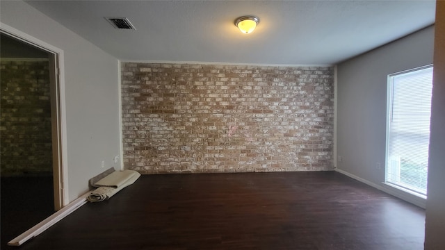 unfurnished room with brick wall and dark hardwood / wood-style floors