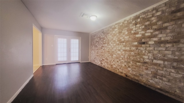 empty room with brick wall, dark hardwood / wood-style floors, and french doors