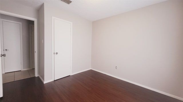 unfurnished bedroom featuring a textured ceiling and dark wood-type flooring