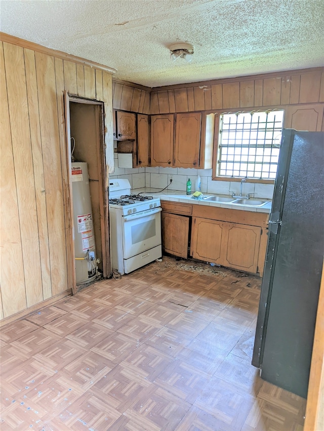 kitchen featuring white gas stove, sink, light parquet flooring, water heater, and black fridge