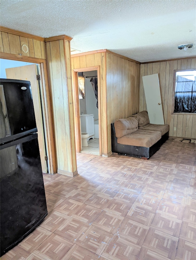 bedroom with a textured ceiling, wooden walls, and light parquet floors