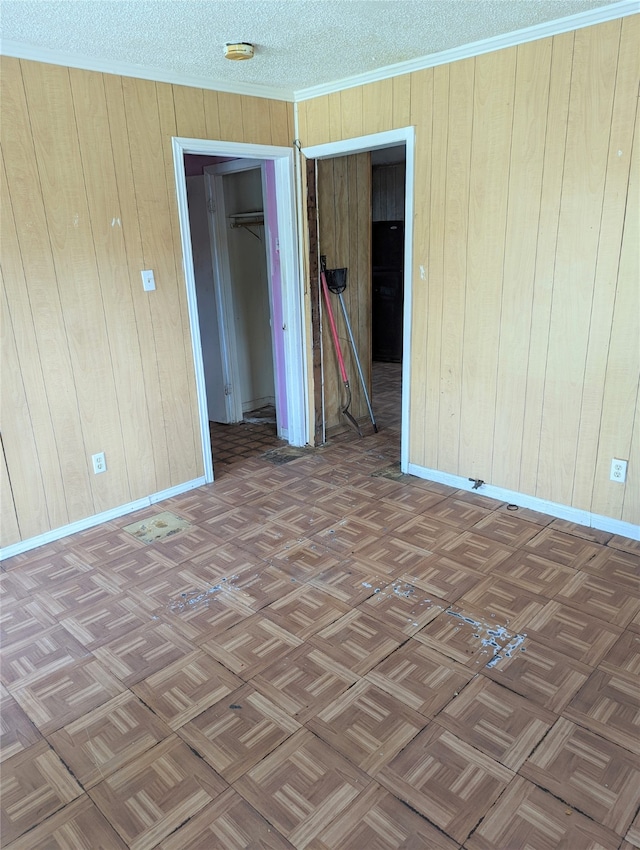 unfurnished room featuring dark parquet floors, a textured ceiling, and wooden walls