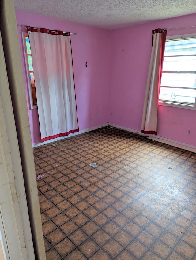 tiled empty room with a textured ceiling