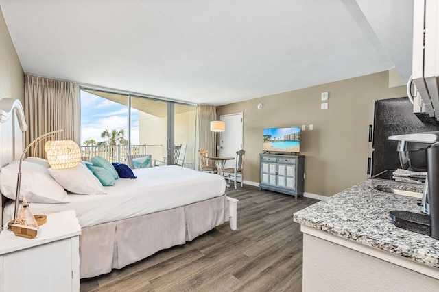 bedroom with a wall of windows, access to outside, and dark hardwood / wood-style floors