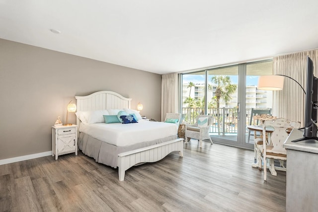 bedroom with hardwood / wood-style floors, floor to ceiling windows, and access to exterior