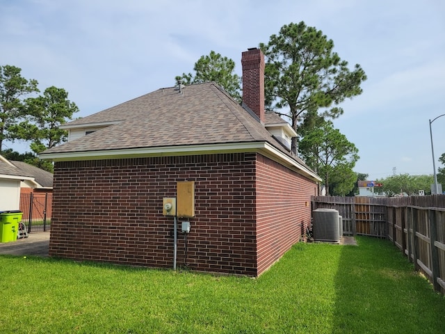 view of side of home featuring central air condition unit and a yard