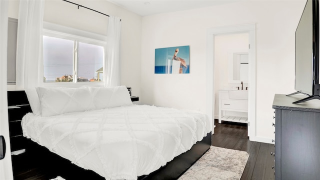 bedroom with connected bathroom and dark hardwood / wood-style flooring