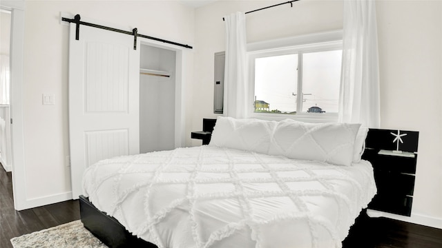 bedroom featuring dark hardwood / wood-style flooring, a barn door, and a closet