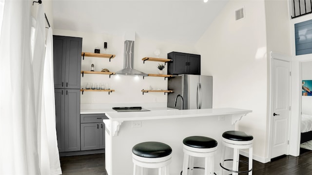 kitchen featuring exhaust hood, dark hardwood / wood-style flooring, a breakfast bar, and fridge