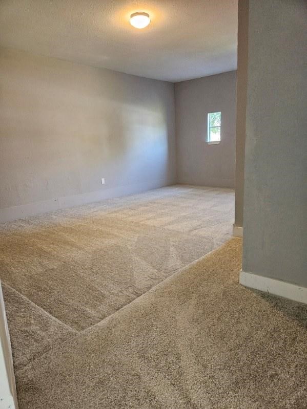 unfurnished room with carpet flooring, a textured ceiling, and baseboards