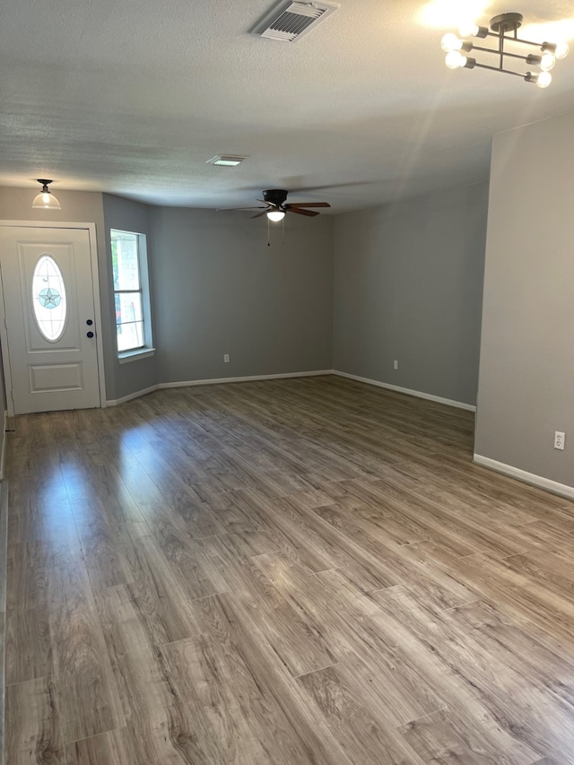 foyer with a textured ceiling, ceiling fan with notable chandelier, and hardwood / wood-style floors