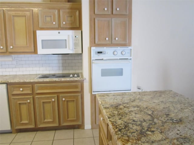 kitchen featuring tasteful backsplash, light stone counters, light tile patterned floors, and white appliances