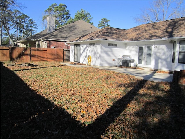 back of house with a patio and a lawn