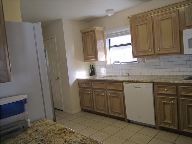 kitchen featuring white appliances, sink, light stone countertops, tasteful backsplash, and light tile patterned flooring