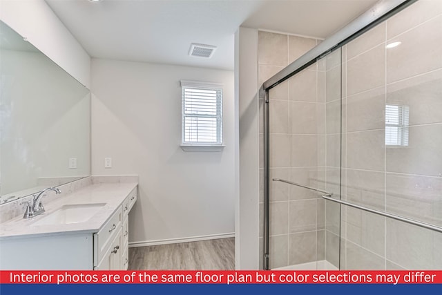 bathroom with large vanity, a shower with shower door, and hardwood / wood-style flooring