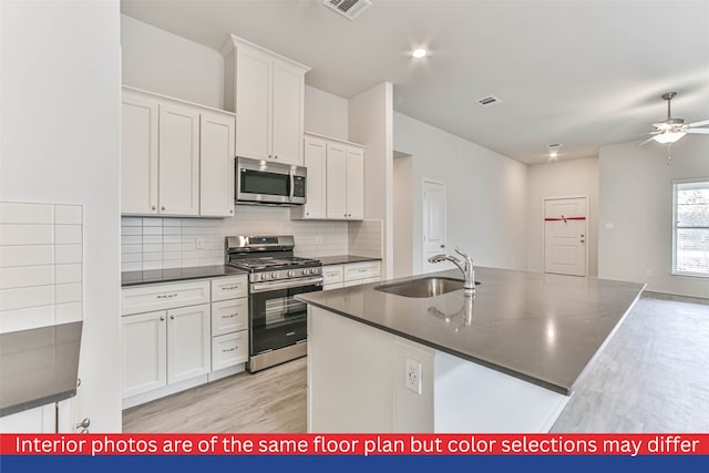 kitchen with white cabinetry, stainless steel appliances, light hardwood / wood-style flooring, ceiling fan, and sink