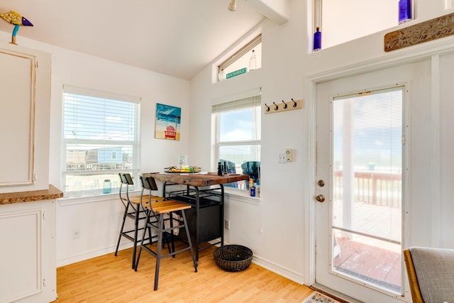 dining room featuring breakfast area, light wood-type flooring, vaulted ceiling, and plenty of natural light