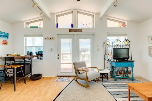 living room with hardwood / wood-style floors, rail lighting, and vaulted ceiling with beams