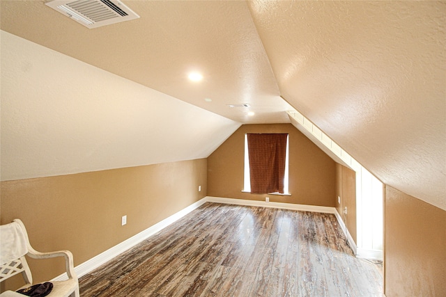 bonus room featuring lofted ceiling, hardwood / wood-style flooring, and a textured ceiling